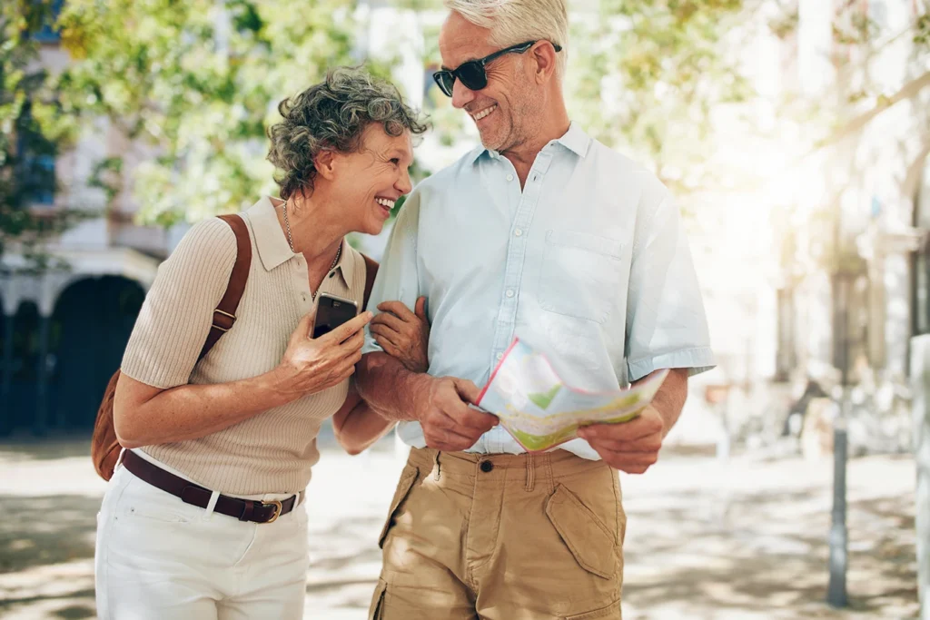 A retired couple, husband and wife, on vacation, holding hands, smiling and laughing, looking at a map, and using hearing aids with language translation